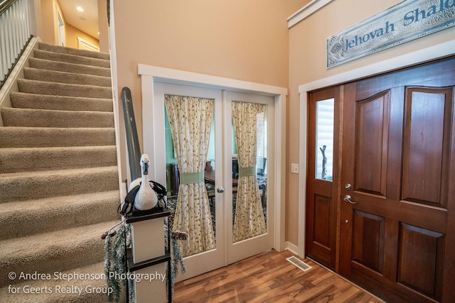 entrance foyer featuring stairs, wood finished floors, and french doors