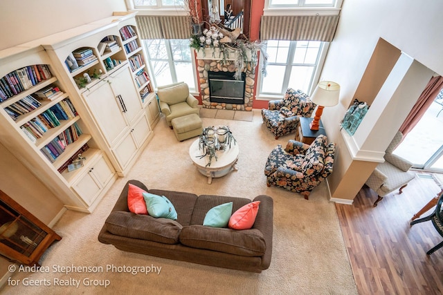 carpeted living area featuring a high ceiling and a stone fireplace