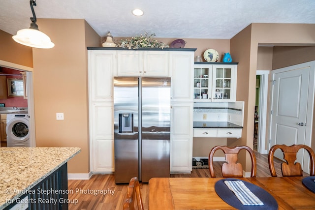 kitchen featuring white cabinets, washer / clothes dryer, stainless steel fridge, glass insert cabinets, and pendant lighting