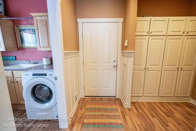 laundry room featuring washer / clothes dryer, a sink, cabinet space, and light wood-style floors