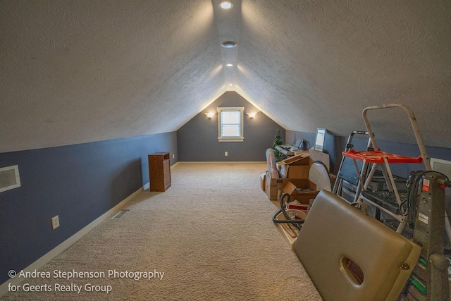 additional living space featuring a textured ceiling, visible vents, vaulted ceiling, and carpet flooring