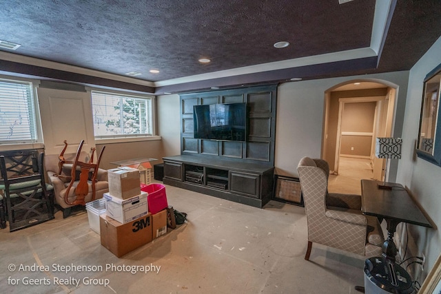 living area featuring arched walkways, visible vents, a raised ceiling, and a textured ceiling