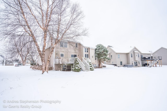 snow covered property with a deck, a residential view, and stairway