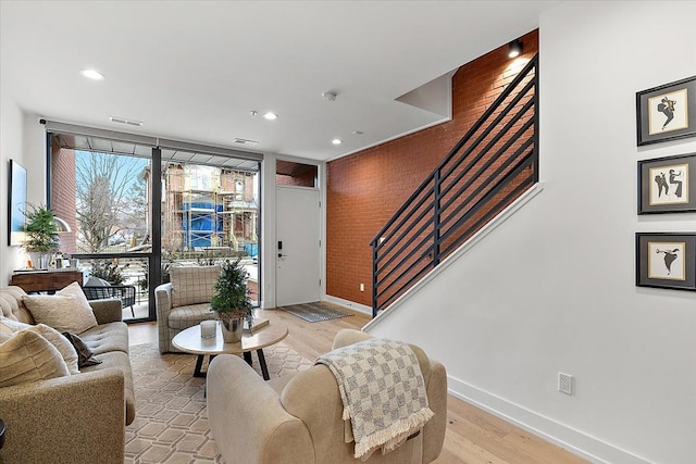 living room with light wood-style floors, baseboards, stairway, and visible vents