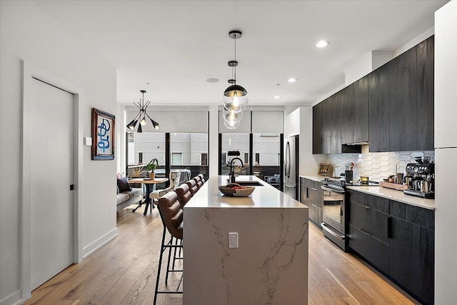 kitchen with a kitchen breakfast bar, stainless steel appliances, backsplash, a sink, and modern cabinets