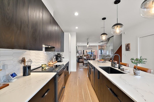 kitchen featuring decorative backsplash, modern cabinets, appliances with stainless steel finishes, a sink, and light wood-type flooring