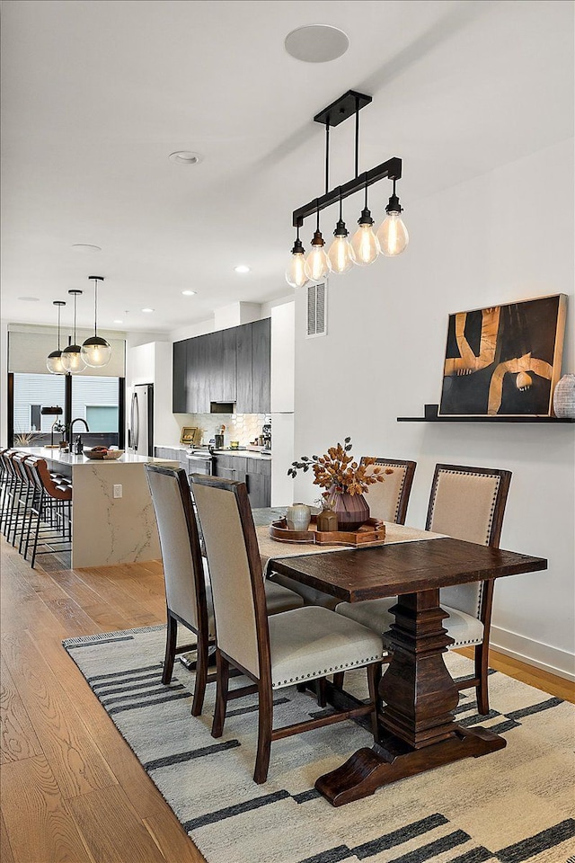 dining room with recessed lighting, baseboards, light wood finished floors, and visible vents