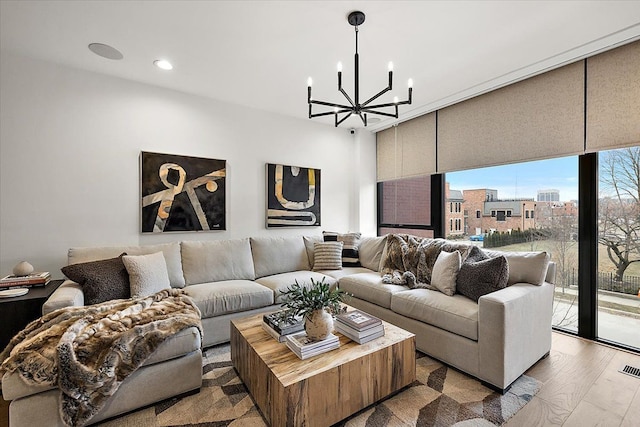 living area with expansive windows, wood finished floors, recessed lighting, and an inviting chandelier