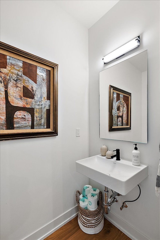 bathroom featuring baseboards, wood finished floors, and a sink