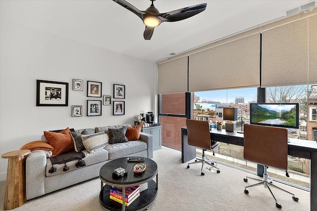 carpeted office space featuring a wall of windows, visible vents, and ceiling fan