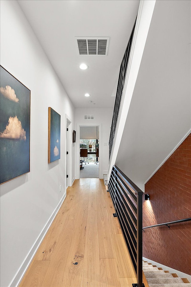hall with wood finished floors, baseboards, stairs, and visible vents