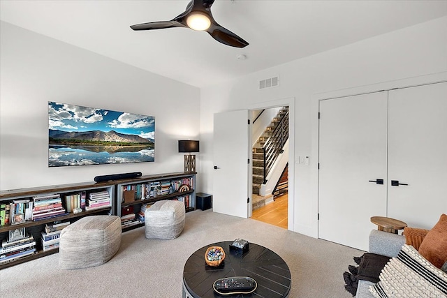 living area with stairs, visible vents, ceiling fan, and carpet floors