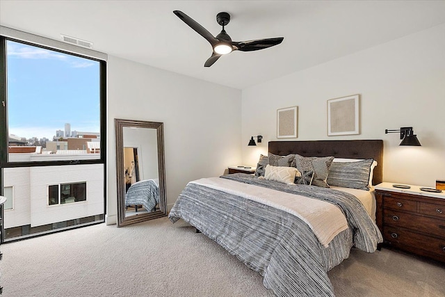 carpeted bedroom featuring expansive windows, ceiling fan, and visible vents