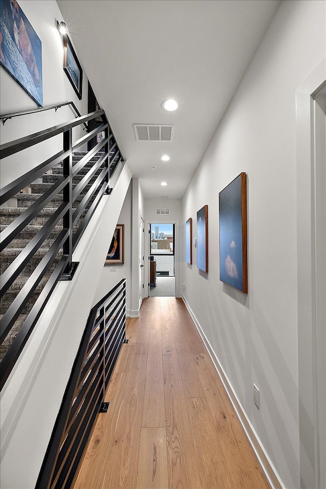 hallway featuring visible vents, baseboards, stairway, recessed lighting, and light wood-style floors