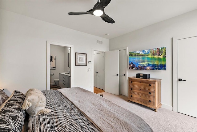 bedroom featuring a ceiling fan, light carpet, ensuite bath, and visible vents