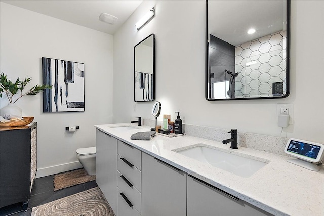 bathroom featuring double vanity, a sink, toilet, and tiled shower