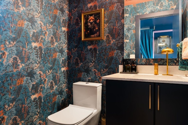 bathroom featuring wallpapered walls, vanity, and toilet
