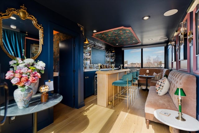 bar with light wood-style floors, recessed lighting, and wet bar