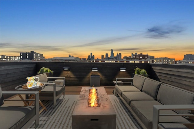 patio terrace at dusk featuring an outdoor living space with a fire pit and a city view