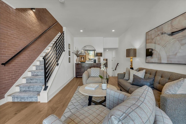 living room with stairs, recessed lighting, baseboards, brick wall, and wood finished floors