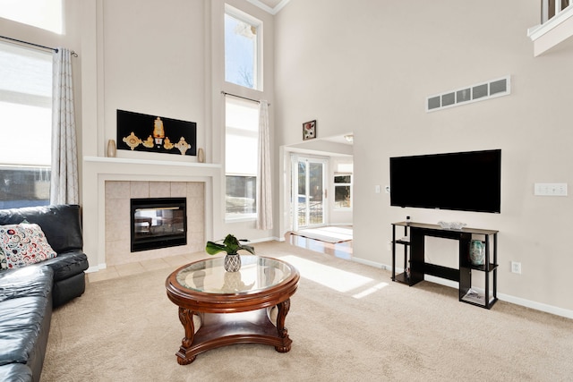 carpeted living room featuring a towering ceiling and a tiled fireplace