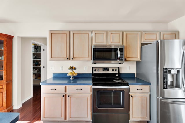 kitchen with stainless steel appliances, light brown cabinetry, and dark hardwood / wood-style flooring