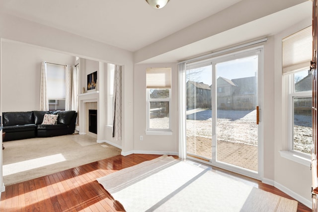 doorway with a tiled fireplace and hardwood / wood-style floors