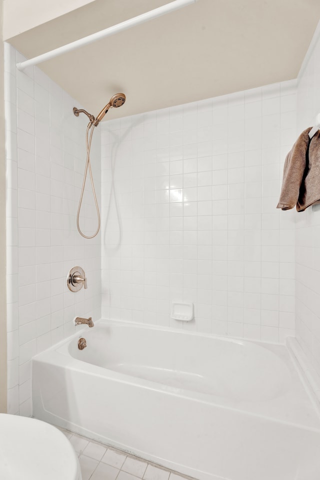 bathroom featuring toilet, tile patterned floors, and tiled shower / bath