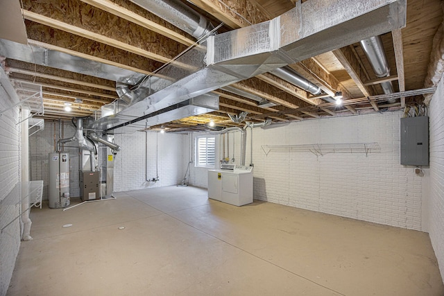 basement featuring electric panel, brick wall, heating unit, water heater, and separate washer and dryer