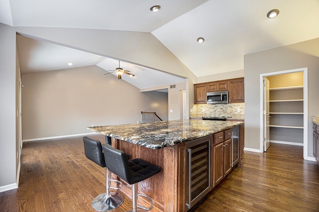 kitchen featuring a kitchen breakfast bar, dark stone countertops, wine cooler, ceiling fan, and backsplash