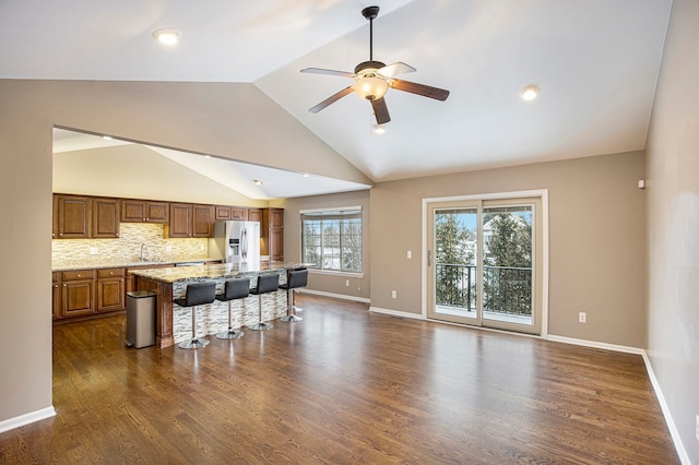 kitchen featuring a center island, ceiling fan, decorative backsplash, stainless steel fridge with ice dispenser, and a breakfast bar