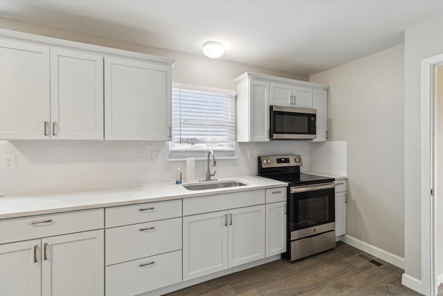 kitchen with sink, dark hardwood / wood-style floors, backsplash, white cabinets, and appliances with stainless steel finishes