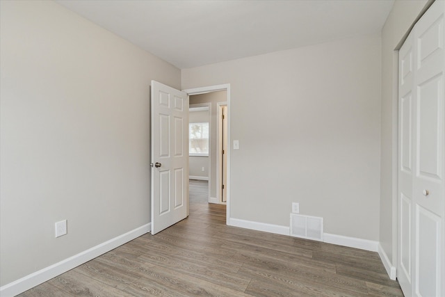 unfurnished bedroom with wood-type flooring and a closet