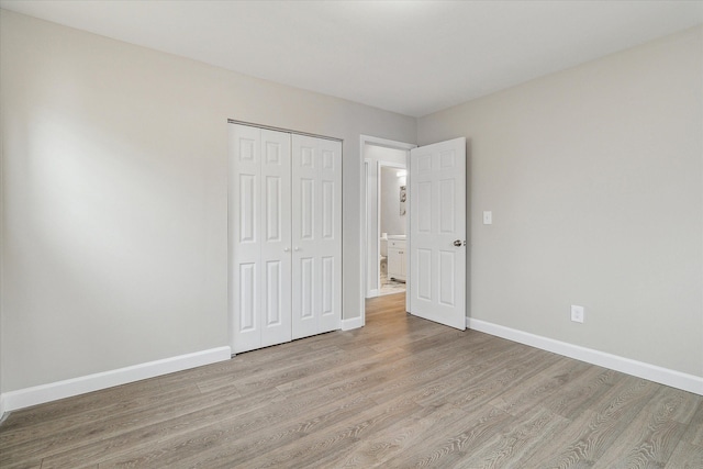 unfurnished bedroom with light wood-type flooring and a closet