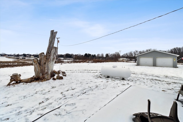 yard layered in snow featuring an outbuilding and a garage