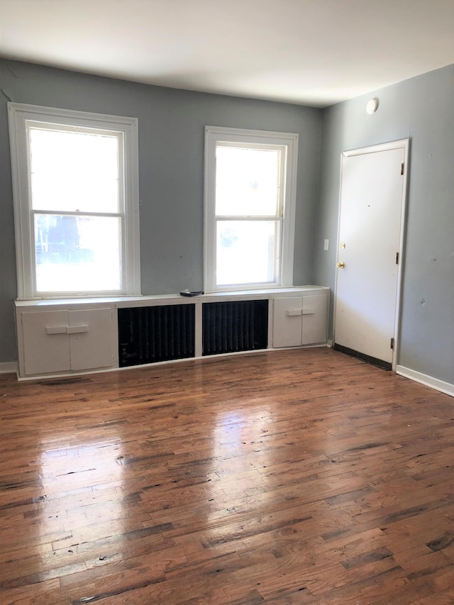 spare room with dark hardwood / wood-style flooring and radiator heating unit