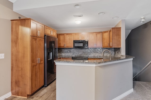 kitchen with stainless steel fridge with ice dispenser, sink, decorative backsplash, dark stone counters, and kitchen peninsula