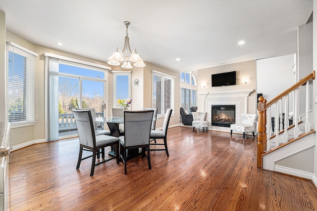 dining space with an inviting chandelier, a tiled fireplace, and hardwood / wood-style floors