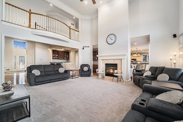 living room featuring a high ceiling, ceiling fan, ornamental molding, and carpet