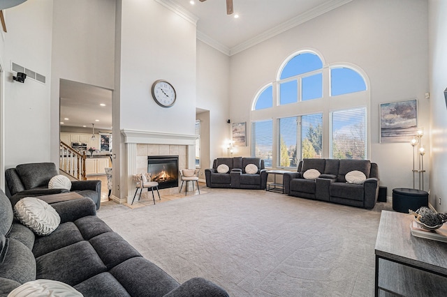 carpeted living room featuring a high ceiling, ornamental molding, and a tile fireplace