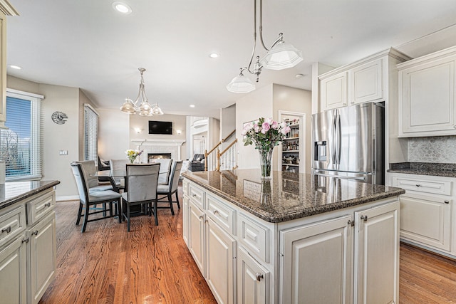 kitchen featuring stainless steel refrigerator with ice dispenser, white cabinets, a center island, and backsplash