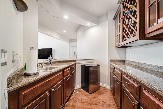 kitchen featuring stone counters, light hardwood / wood-style floors, dark brown cabinets, and sink