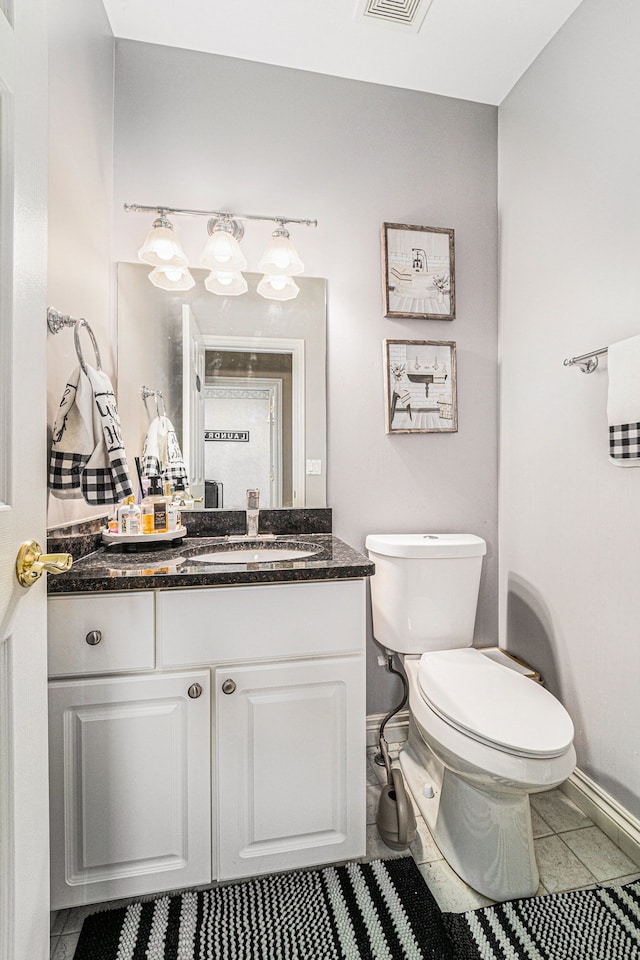 bathroom with toilet, vanity, and tile patterned floors