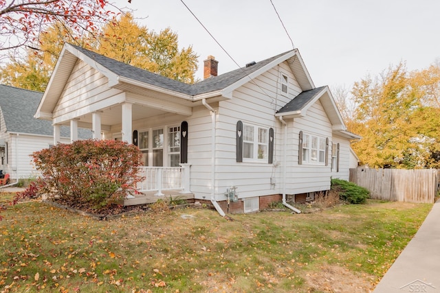 view of home's exterior with covered porch and a lawn