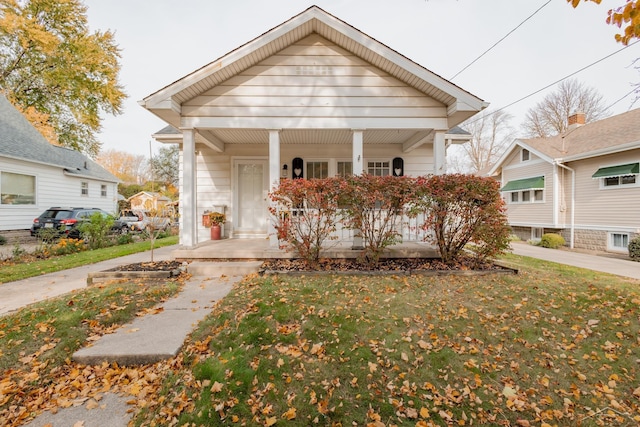 bungalow-style home featuring covered porch and a front yard