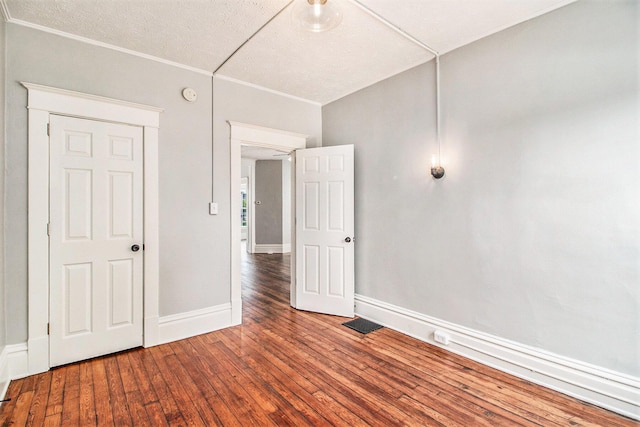 unfurnished room with wood-type flooring, a textured ceiling, and ornamental molding