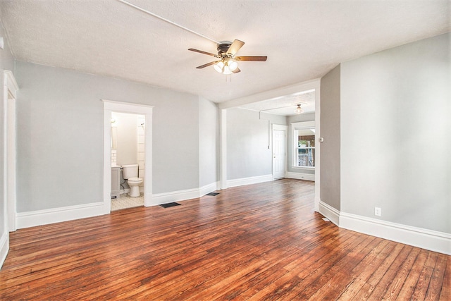 empty room with a textured ceiling, ceiling fan, and dark hardwood / wood-style floors