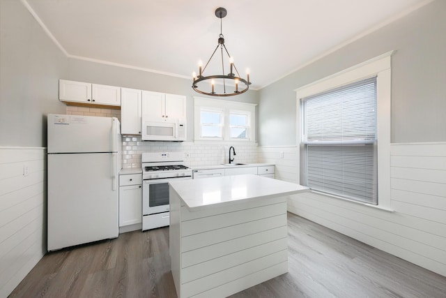 kitchen with white cabinetry, an inviting chandelier, crown molding, decorative light fixtures, and white appliances