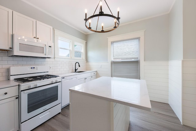 kitchen with white cabinetry, sink, an inviting chandelier, pendant lighting, and white appliances