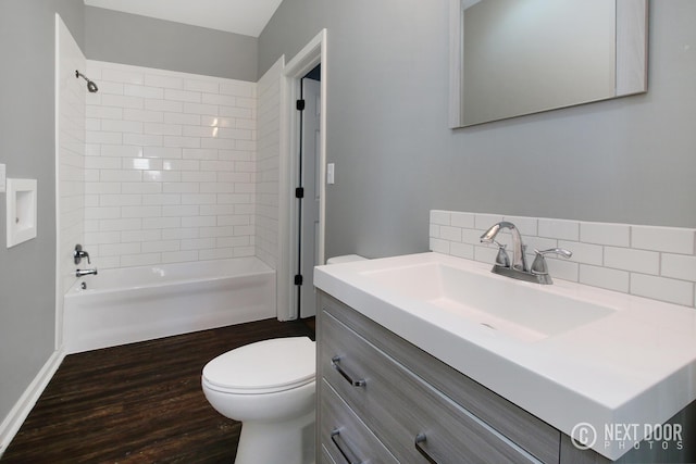 full bathroom with tiled shower / bath combo, wood-type flooring, toilet, decorative backsplash, and vanity